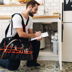 Image of plumber man with equipment and clipboard working in apartment